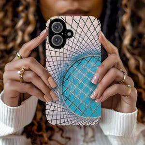 May include: A smartphone case with a geometric design, featuring a blue sphere and a grid pattern. The case has a dual-lens camera. The case is held by a person with manicured nails and gold rings. The design creates an optical illusion.