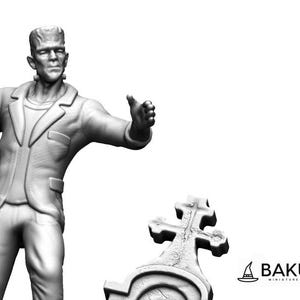 Peut inclure: Une miniature peinte en gris de la créature de Frankenstein en costume, debout, le bras droit levé et la main ouverte. La miniature est debout devant une miniature peinte en gris d'une pierre tombale avec une croix.