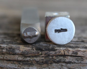 Pode incluir: Dois carimbos de metal, um com um design de linha horizontal e o outro com um design de linha vertical. Os carimbos são usados para carimbar metal.