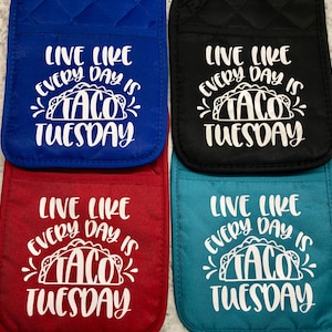 May include: Four pot holders with the text "Live Like Every Day Is Taco Tuesday" in white lettering on a blue, black, red, and teal background.