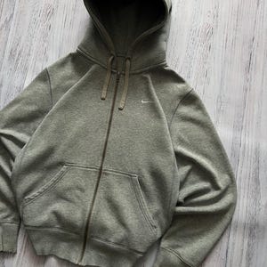 Puede incluir: Una sudadera gris con cremallera, capucha con cord&oacute;n y bolsillos delanteros. El logotipo de Nike est&aacute; bordado en el pecho izquierdo. La sudadera con capucha est&aacute; hecha de un material suave y c&oacute;modo.