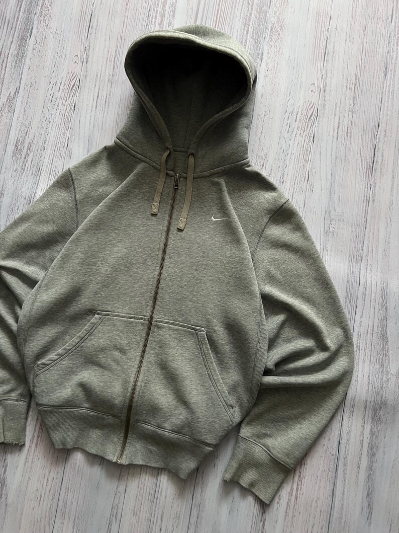 Puede incluir: Una sudadera gris con cremallera, capucha con cord&oacute;n y bolsillos delanteros. El logotipo de Nike est&aacute; bordado en el pecho izquierdo. La sudadera con capucha est&aacute; hecha de un material suave y c&oacute;modo.