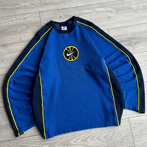 May include: A blue sweatshirt with black and yellow accents. The sweatshirt features a basketball logo on the chest and black stripes with yellow trim along the sleeves. The Nike logo is visible on the upper chest.