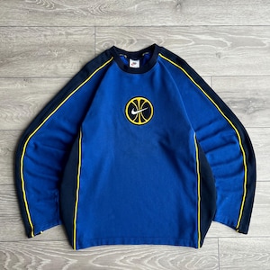 May include: Blue long-sleeve sweatshirt with a basketball graphic. The sweatshirt has black sleeves with yellow trim and a black collar. A yellow and black basketball logo is centered on the chest. The Nike logo is on the collar.