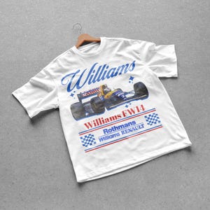 以下が含まれることがあります： ヴィンテージのWilliams FW14レーシングカーのデザインが施された白いTシャツ。シャツには青い筆記体で「Williams」と、赤と青で「Rothmans Williams Renault」と書かれています。デザインにはレーシングカーのグラフィックが含まれています。