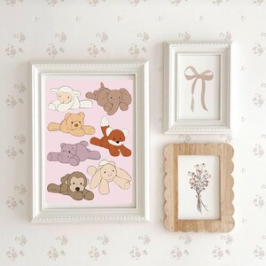 May include: A white frame with a pink background featuring a collection of eight stuffed animal illustrations. The animals include a sheep, elephant, bear, fox, hippopotamus, rabbit, and monkey. The illustrations are in a cartoon style.