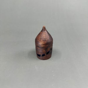 Puede incluir: Un pequeño recipiente de cerámica marrón de punta con acentos azules. El recipiente tiene una superficie texturizada.