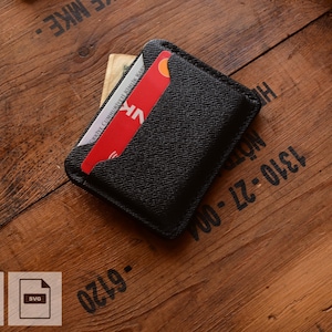 Könnte beinhalten: Schwarzer Lederkartenhalter mit einer rot-weißen Kreditkarte, die teilweise sichtbar ist. Der Kartenhalter liegt auf einer Holzoberfläche. Das Bild enthält auch PDF- und SVG-Dateisymbole.