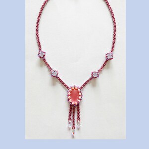 May include: A pink and blue beaded necklace with a large pink pendant. The necklace is called "Rosa Blu Necklace" by Carmelina Calabrese.