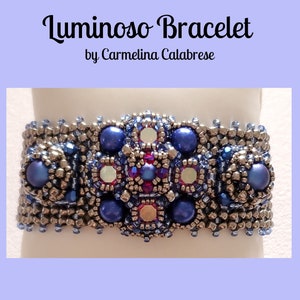 May include: A beaded bracelet with a silver and blue colour scheme. The bracelet features a central design of blue and silver beads, with a red and silver accent. The bracelet is called "Luminoso Bracelet" by Carmelina Calabrese.
