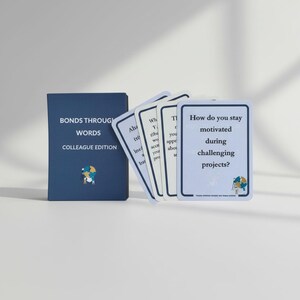 Puede incluir: Una caja de juego de cartas azul marino y varias cartas con bordes blancos. La caja dice "BONDS THROUGH WORDS" y "COLLEAGUE EDITION". Una tarjeta pregunta: "¿Cómo te mantienes motivado durante proyectos desafiantes?"