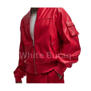 May include: A vibrant red bomber jacket with a zip-up front and two front pockets. The jacket has a ribbed hem and cuffs. The text "White Buraq" is visible on the lower part of the jacket.