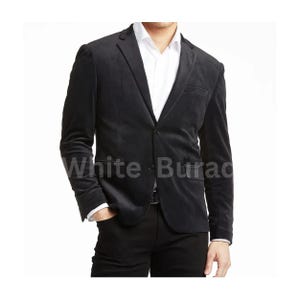 May include: A black velvet blazer with a single-button closure, paired with black pants and a white dress shirt. The blazer has a notched lapel and a chest pocket. The text "White Burac" is visible on the blazer.