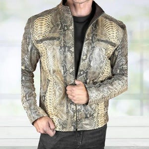 May include: A snakeskin-patterned leather jacket in shades of tan, brown, and gray. The jacket features a zip-up front, two zippered chest pockets, and a stand-up collar. The jacket is a stylish outerwear piece.