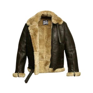 May include: A brown leather jacket with a shearling lining and collar. The jacket has a zipper closure, a buckle at the waist, and shearling trim on the cuffs. The label "WHITE BURAQ" is visible on the collar.