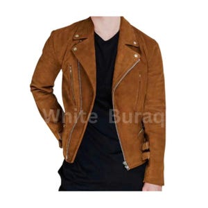 May include: A brown suede biker jacket with a notched collar, asymmetrical zipper closure, and multiple zippered pockets. The jacket features silver hardware and buckle details at the waist. The text "White Buraq" is visible on the jacket.