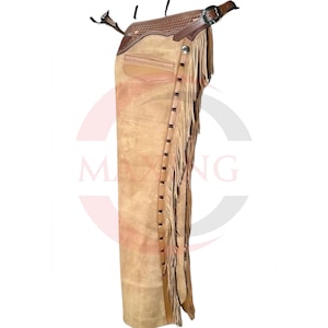 May include: Tan suede leather chaps with a brown leather waistband and accents. The chaps feature a fringe along the sides and decorative stitching. A buckle and strap secure the chaps at the waist.