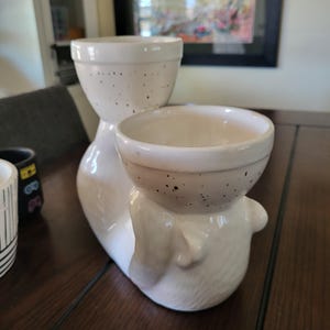May include: White ceramic planter with two pots. The planter is shaped like a stylized animal with a speckled brown glaze. The pots are also speckled brown.