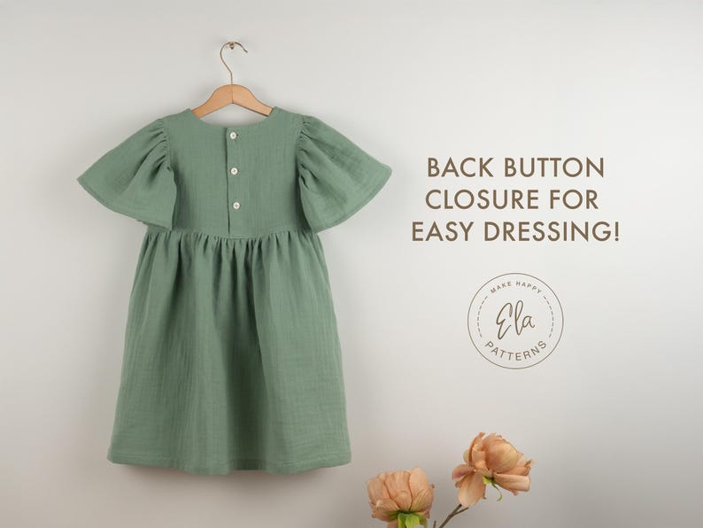 May include: A sage green dress with flutter sleeves hangs on a wooden hanger. The dress features a back button closure and a gathered skirt. Text on the right reads "BACK BUTTON CLOSURE FOR EASY DRESSING!" with a circular logo below.