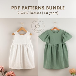 Op de afbeelding: Afbeelding van twee meisjesjurken aan houten hangers. Eén is wit met een textuurpatroon, de andere is saliegroen met pofmouwen. De tekst bovenaan luidt "PDF PATTERNS BUNDLE 2 Girls' Dresses (1-8 years)".