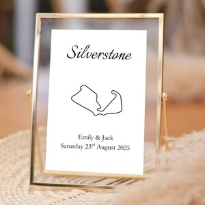 Könnte beinhalten: Gerahmter Druck mit dem Wort "Silverstone" in Schreibschrift. Darunter befindet sich eine schwarz-weiße Umrisszeichnung der Rennstrecke von Silverstone. Der Text "Emily & Jack" und das Datum "Samstag, 23. August 2025" sind ebenfalls enthalten.