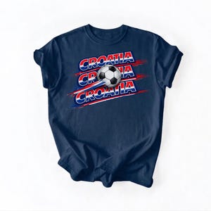 May include: Navy blue t-shirt featuring the word "CROATIA" in red, white, and blue, with a soccer ball graphic. The design includes three instances of the word "CROATIA" with a soccer ball in the center.
