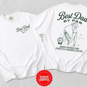 May include: A white t-shirt featuring a dark green graphic. The front displays the text Best Dad By Par. The back shows a golfer with a bag, a badge reading Number 1, and the text Best Dad By Par, Above Average Dad, Perfectly Average Golfer.