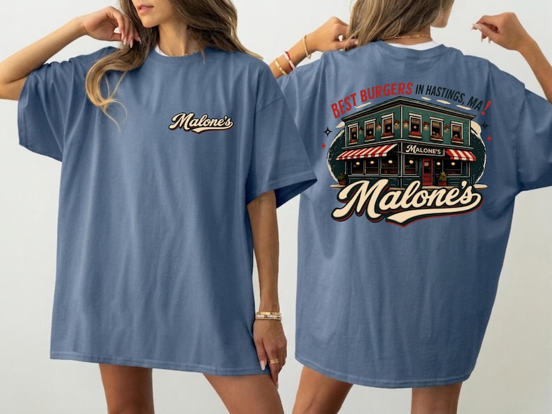 May include: A blue t-shirt with the Malone's logo on the front and a restaurant graphic on the back, with the text "Best Burgers in Hastings, MA!". The shirt has a loose fit.