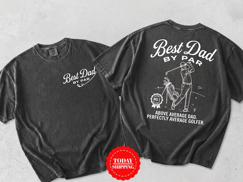 May include: A charcoal gray short-sleeve t-shirt featuring white graphics. The front displays the text "Best Dad BY PAR". The back shows a golfer, a golf bag, a "RANKED NO.1" badge, and the text "Best Dad BY PAR. ABOVE AVERAGE DAD. PERFECTLY AVERAGE GOLFER."