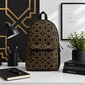 May include: Black backpack with a gold geometric pattern. The backpack has a front pocket, a top handle, and adjustable straps. The design is repeated across the entire surface. The backpack is sitting on a white surface.
