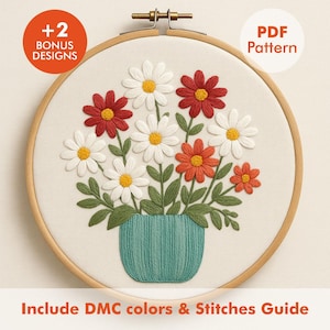 Puede incluir: Diseño floral bordado con margaritas rojas, blancas y naranjas en un jarrón turquesa, en un aro de madera. El texto incluye "+2 Bonus Designs", "PDF Pattern" y "Include DMC colors & Stitches Guide".