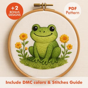 May include: A cross-stitch embroidery hoop featuring a smiling green frog with black eyes, sitting on green grass, and surrounded by yellow flowers. The text "+2 BONUS DESIGNS" and "PDF Pattern" are visible. The text "Include DMC colors & Stitches Guide" is also visible.