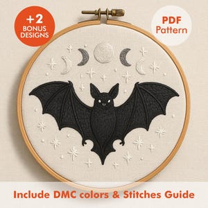May include: A black bat with outstretched wings is embroidered on a cream-colored fabric, surrounded by embroidered stars and crescent moons. The design is set in a wooden embroidery hoop. Text includes "+2 Bonus Designs", "PDF Pattern", and "Include DMC colors & Stitches Guide".