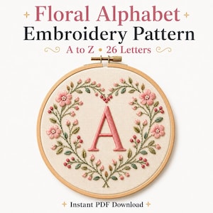 Puede incluir: Un bastidor de bordado circular de madera con tela color hueso que presenta una letra A bordada en rosa, rodeada por una corona en forma de corazón de flores rosas, capullos y hojas verdes. El texto dice: Floral Alphabet Embroidery Pattern A to Z 26 Letters.