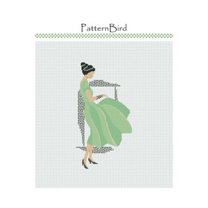 May include: A green dress with a geometric pattern, worn by a woman with dark hair and a green headband. The woman is standing in front of a white background.