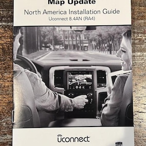May include: A black and white image of a Uconnect Navigation Map Update guide. The guide includes the text "North America Installation Guide" and "Uconnect 8.4AN (RA4)". The image also shows a car's dashboard with a navigation screen and two people in the car.