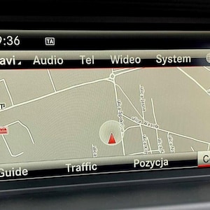 Może przedstawiać: Ekran nawigacji samochodowej wyświetlający mapę ulic z czerwonym znacznikiem lokalizacji. Na ekranie widnieje godzina 9:36 oraz opcje Navi, Audio, Tel, Video i System.