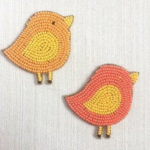 May include: Two beaded bird ornaments, one orange and yellow, the other pink and yellow.