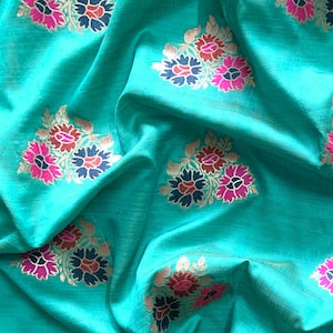 May include: Teal fabric with a repeating pattern of gold, pink, and black floral designs.