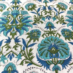 May include: A white fabric with a blue and green floral pattern. The pattern features intricate designs of flowers and leaves.