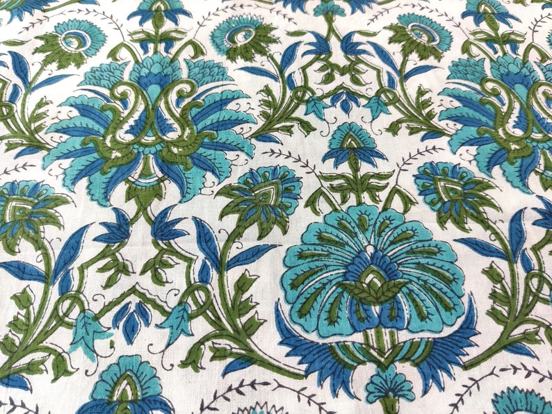May include: A white fabric with a blue and green floral pattern. The pattern features intricate designs of flowers and leaves.
