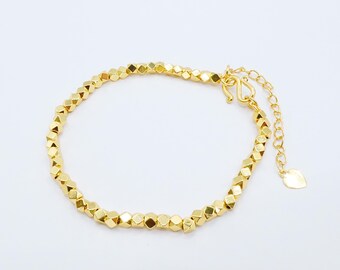 Puede incluir: Pulsera dorada con una serie de cuentas geométricas facetadas. La pulsera tiene una delicada cadena con una longitud ajustable y un dije en forma de corazón. El cierre es de tipo gancho y ojo.