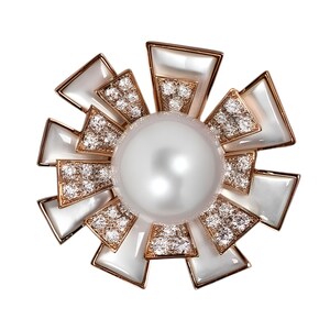 May include: A sunburst-shaped brooch with a large, lustrous pearl center. The brooch features diamond accents and white, geometric shapes set in a gold-tone metal. The design is elegant and eye-catching, suitable for formal wear.