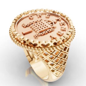 Peut inclure: Une bague dorée avec une face en forme de pièce de monnaie. La bague présente une bande texturée avec un motif en losange et une bordure en forme de corde autour de la pièce. La pièce porte l'inscription "ONE PENNY".