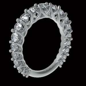Può includere: Un anello eternity in argento con numerosi diamanti taglio rotondo incastonati in una montatura a griffe condivisa. L'anello è presentato su uno sfondo nero, evidenziando la brillantezza delle gemme. È un gioiello.