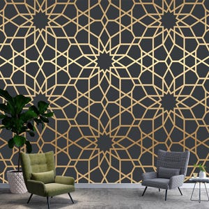May include: A dark grey wall featuring a gold geometric pattern. The pattern is a repeating design of stars and interlocking shapes. A green armchair, a black and white patterned chair, and a potted plant are in front of the wall.