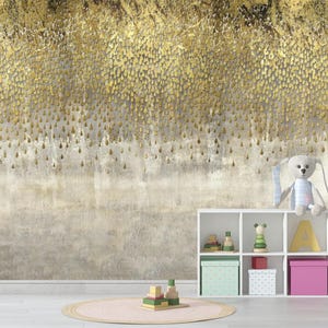 May include: A gold and beige abstract wallpaper design with a textured appearance. The wallpaper features a pattern of gold droplets cascading down a beige background. A white shelf holds toys and a stuffed bunny.