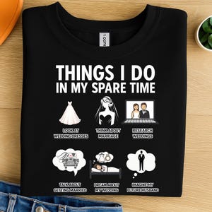 May include: Black t-shirt with white text and graphics. The text reads "THINGS I DO IN MY SPARE TIME" with illustrations of wedding-related activities, including looking at dresses and dreaming about weddings.