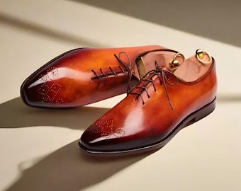 May include: A pair of brown leather lace-up shoes with a burnished finish and decorative perforations. The shoes have a classic oxford style and are made of high-quality leather.