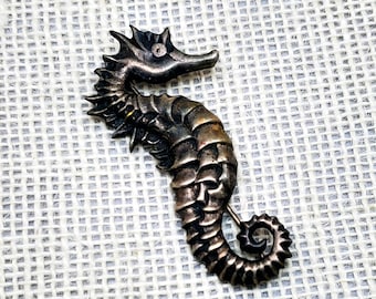 metal and glass gold colour slightly pinkish and black. Enamelled brooch Seahorse
